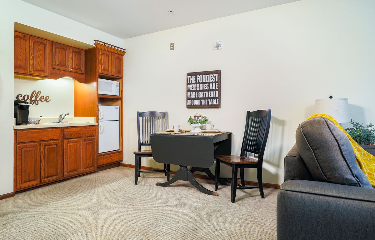 A cozy dining space with a small table and chairs adjacent to a kitchen with wooden cabinets.