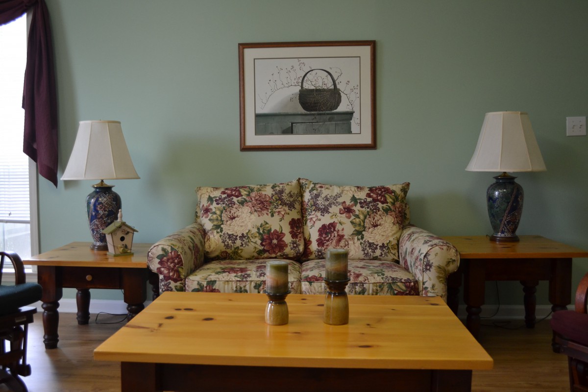 A cozy living room with a floral-patterned sofa, wooden coffee table, and decorative lamps.