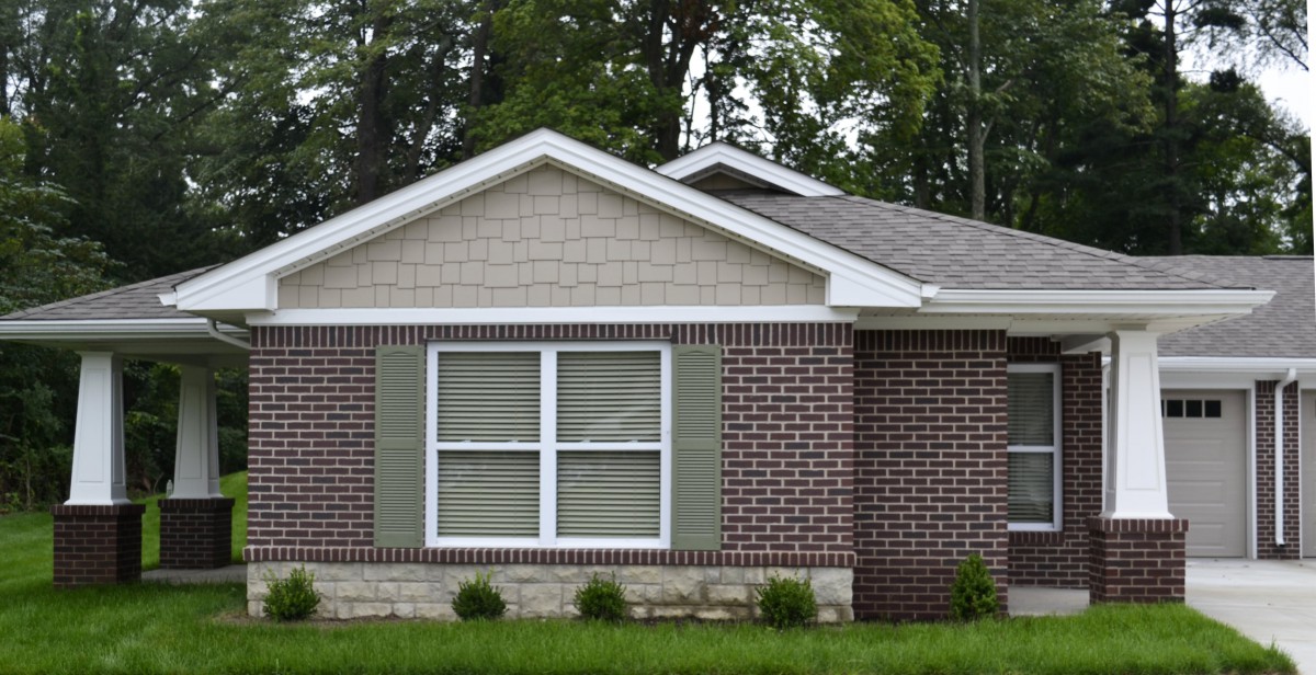 A suburban brick house with a gabled roof and large windows.