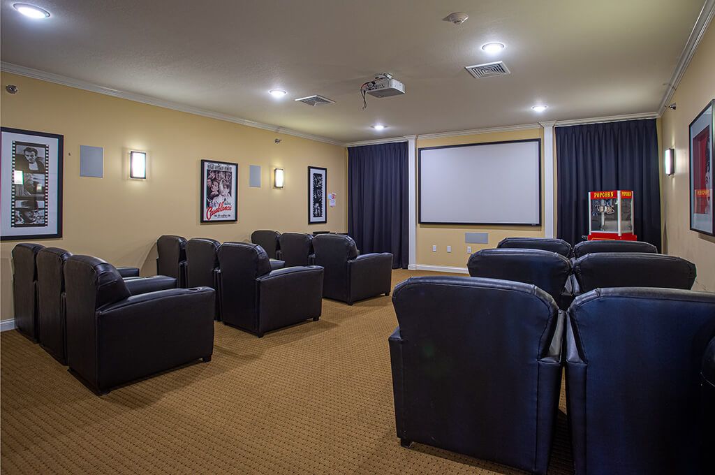 A cozy home theater room with comfortable seating, a large projector screen, and wall posters.
