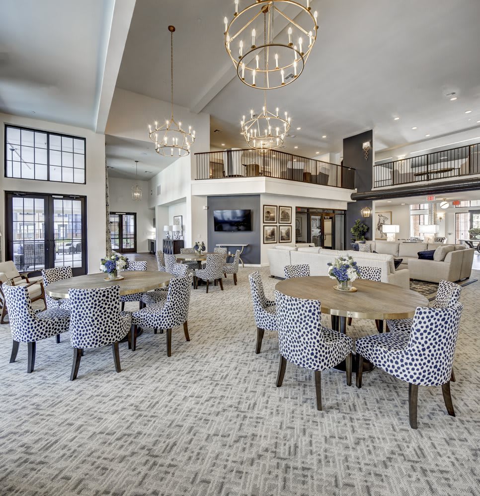A spacious and elegantly designed dining area featuring modern furniture and large chandeliers.