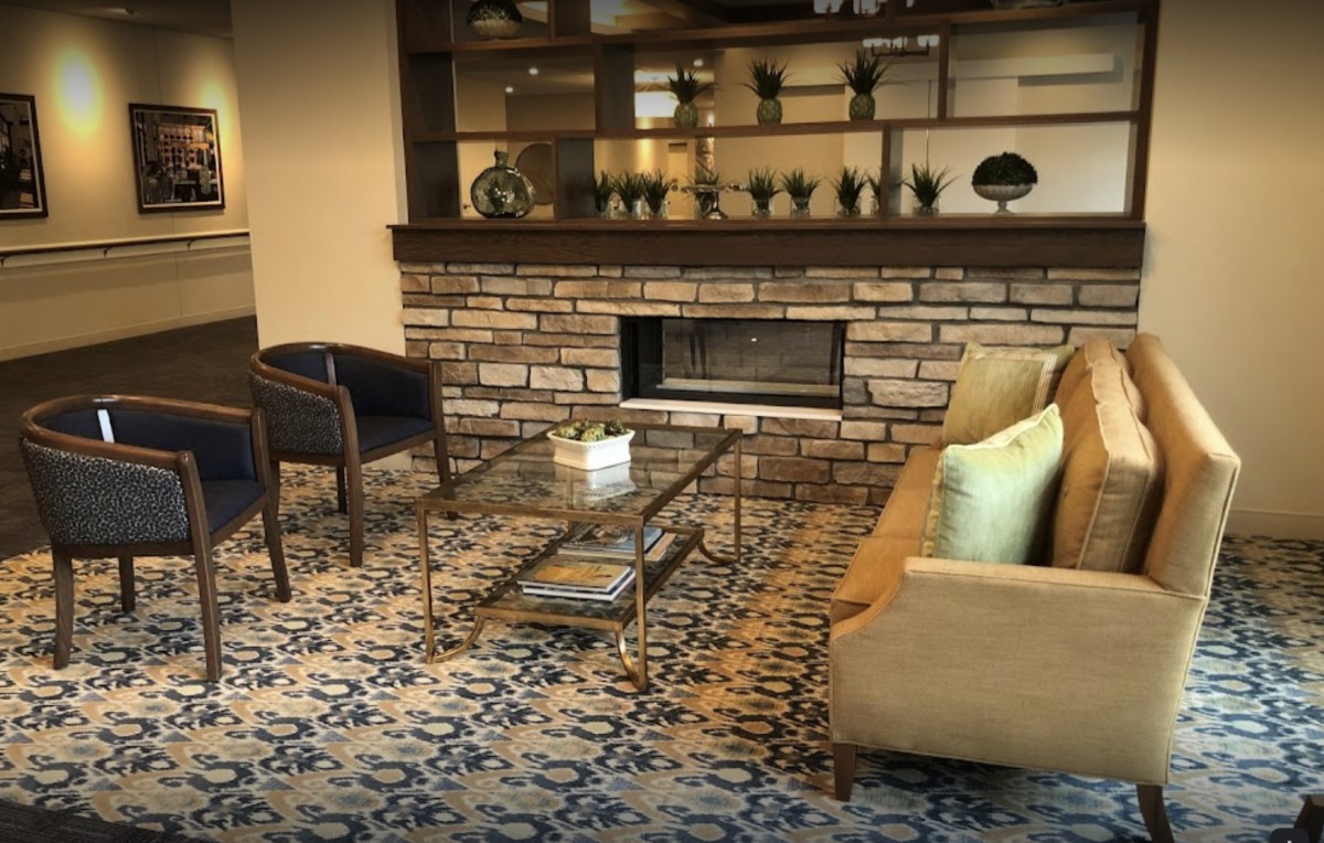 A cozy living room with modern furniture, featuring a fireplace and well-decorated shelves.