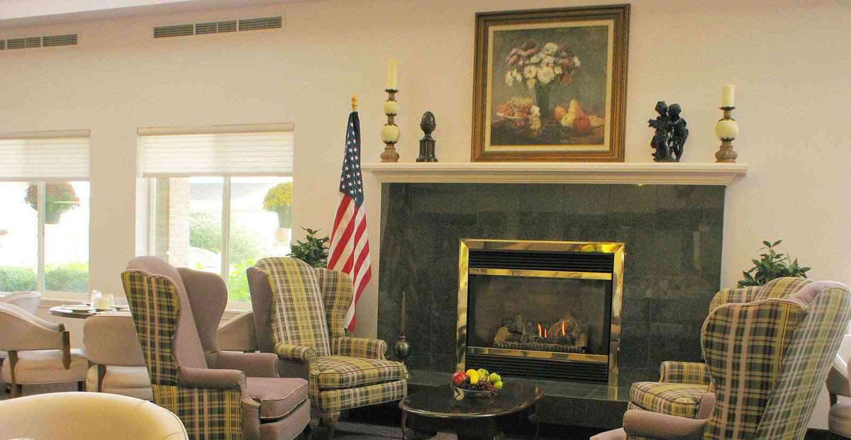 A cozy living room with a fireplace, armchairs, and an American flag.