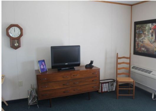 A simple room setup with a wooden dresser, television, and chair.