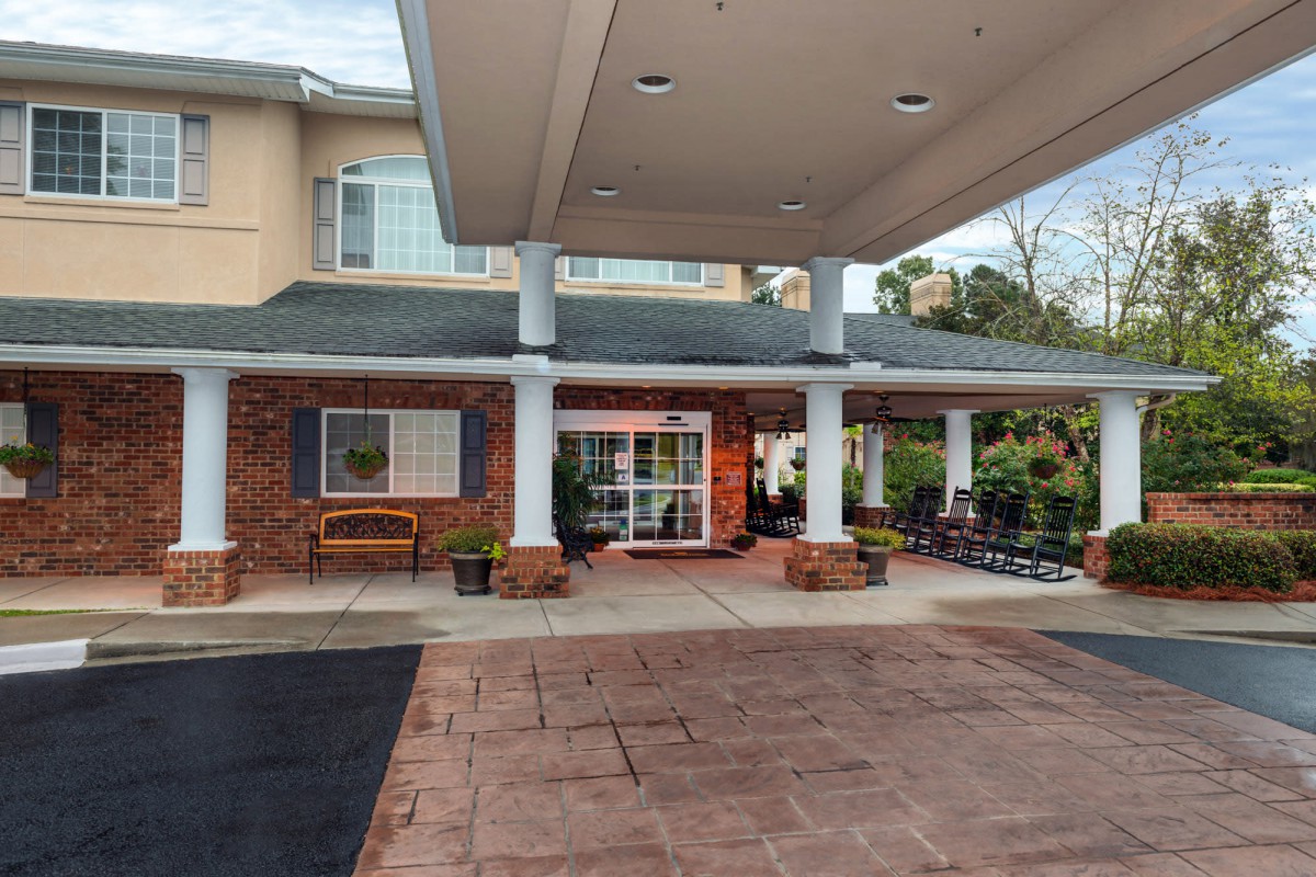 The entrance of a building with an awning and landscaped surroundings.