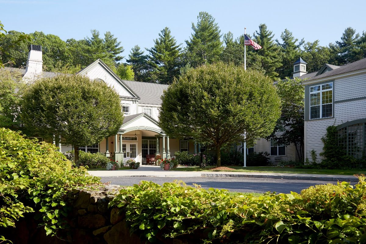 A scenic view of a building surrounded by lush greenery and trees, with a clear blue sky above.