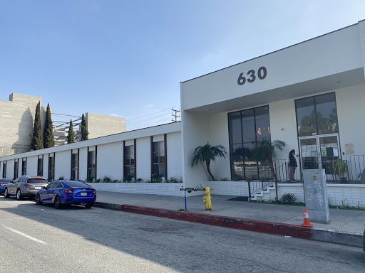 A modern commercial building with a blue car parked outside, featuring the number 630 on its facade.