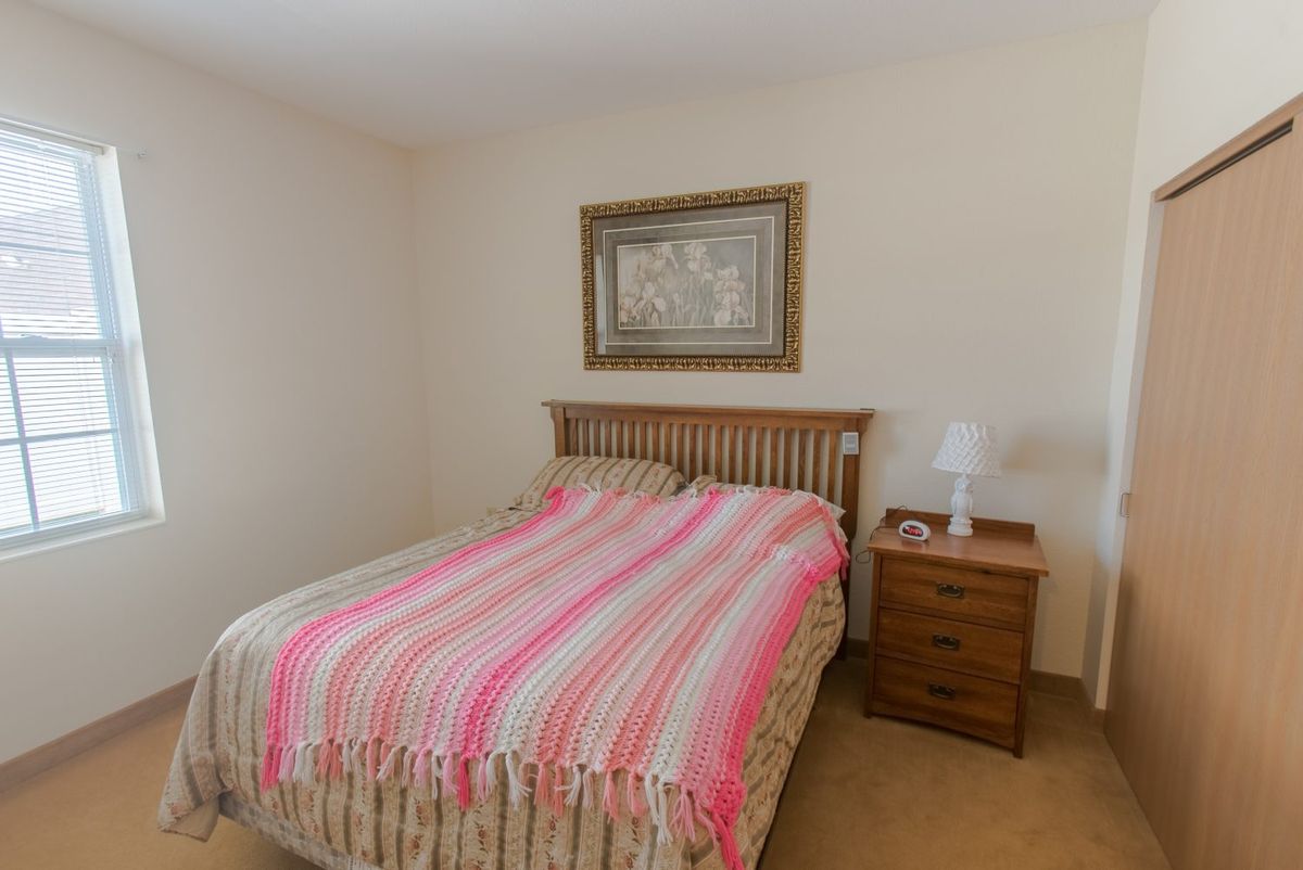 A cozy bedroom with a striped bedspread, wooden nightstand, and framed artwork.
