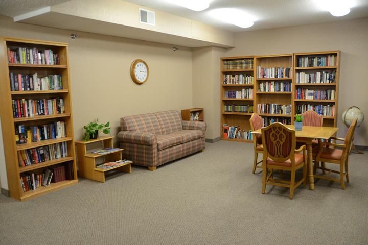 A cozy reading room with bookshelves, a sofa, and a table with chairs.