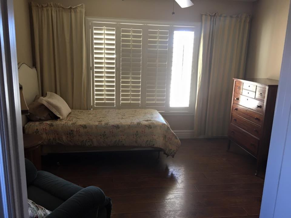 A cozy bedroom with a bed, curtains, and wooden flooring.