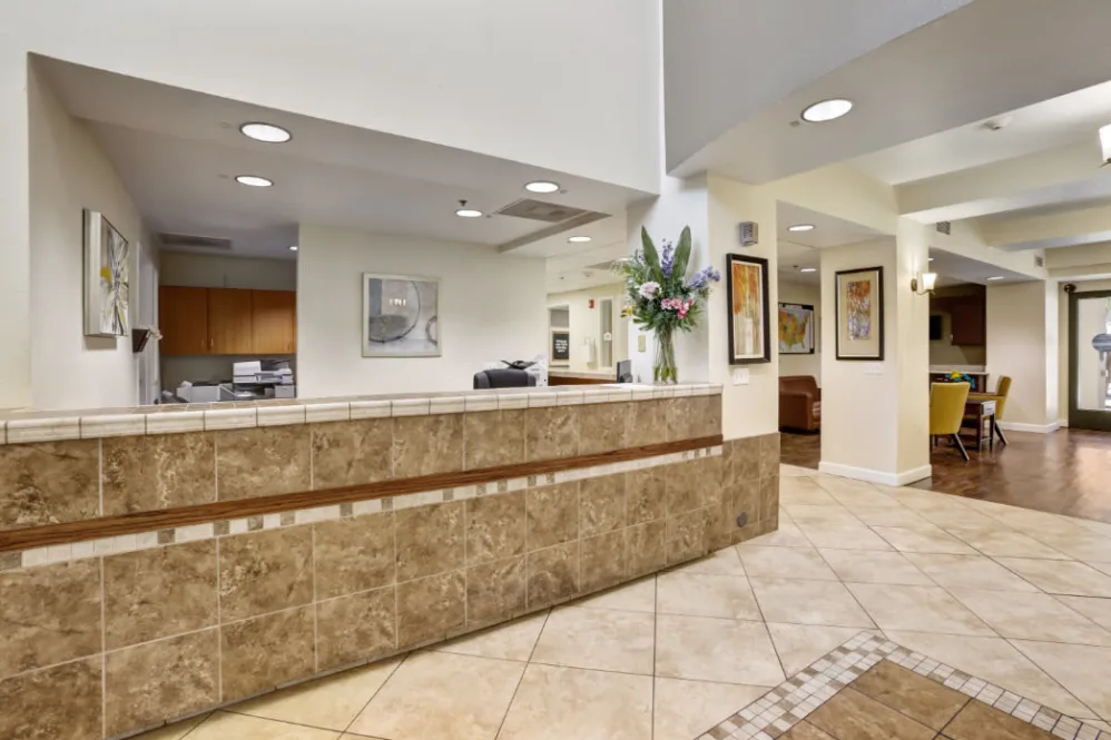 A modern office lobby with a tiled reception desk and decorative artwork on the walls.