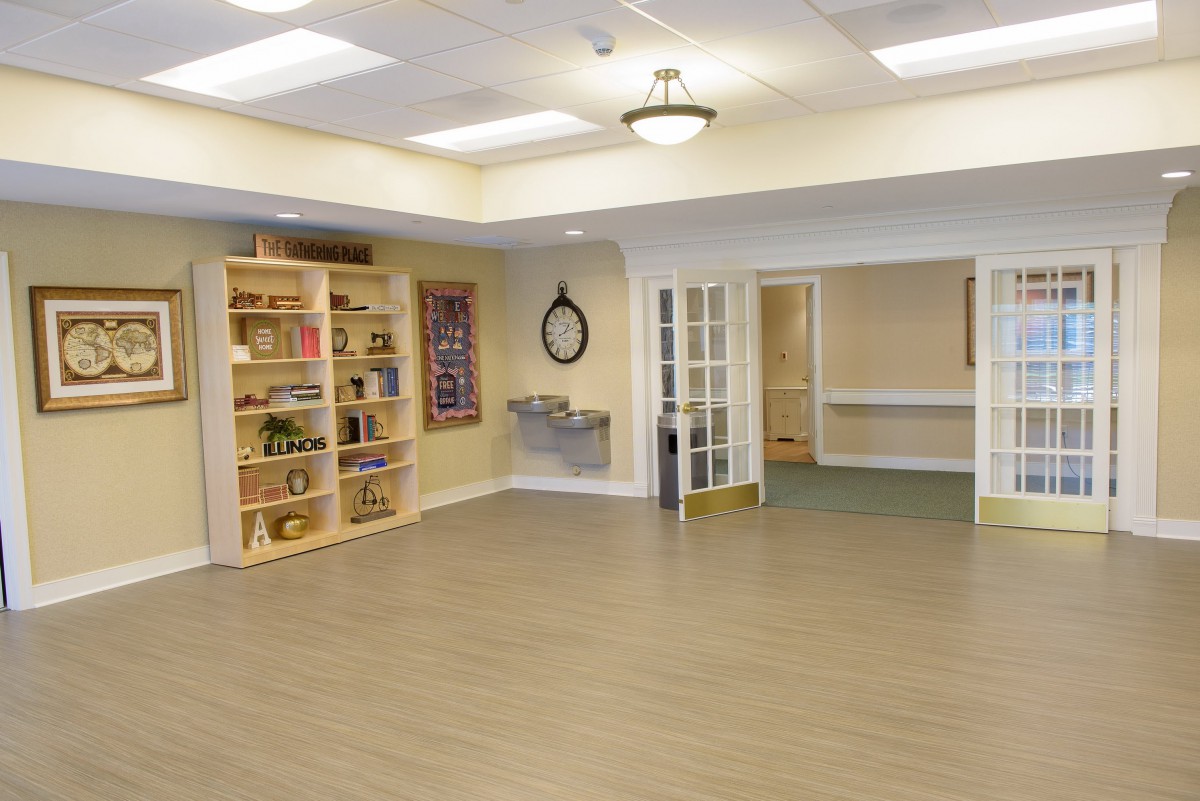 An empty, bright room featuring a bookshelf and open doorways.