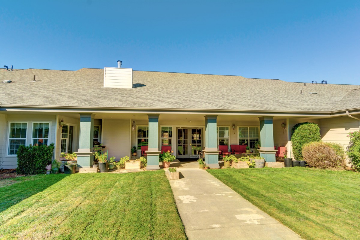 A single-story house with a well-maintained front lawn and a spacious porch.