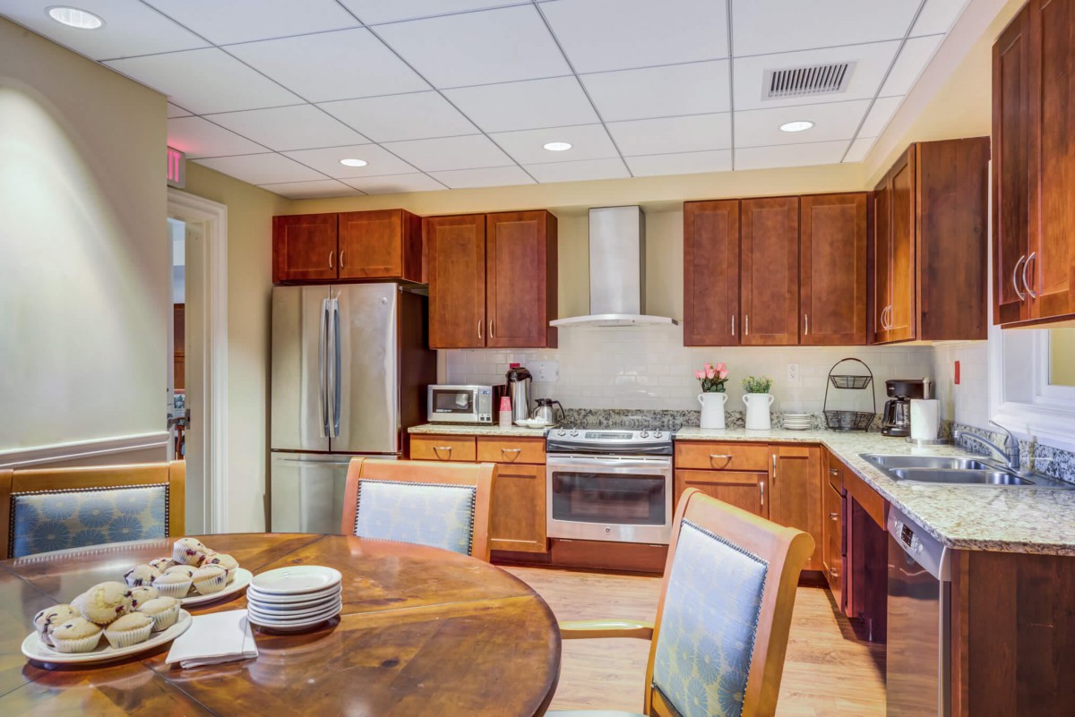 A modern kitchen with wooden cabinets and a dining table.