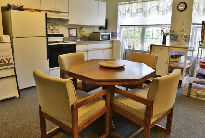 A cozy kitchen with a wooden dining table and upholstered chairs.