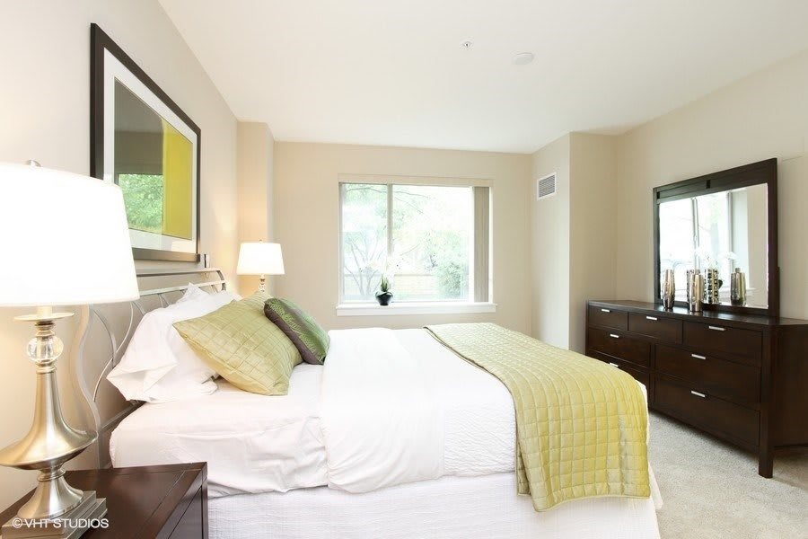 A bright and modern bedroom with a large bed, soft lighting, and neutral decor.