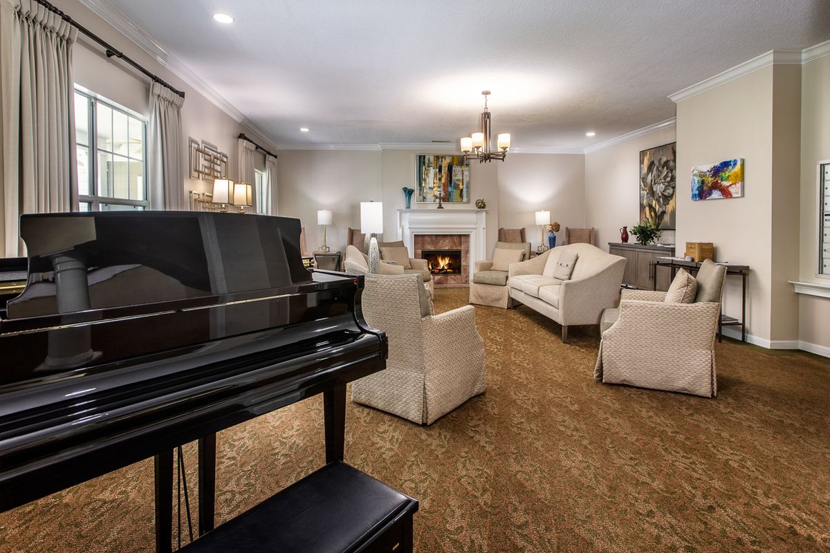 A spacious living room featuring a grand piano, fireplace, and elegant furnishings.