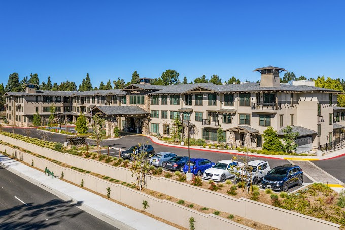 A modern three-story building with a parking lot and landscaped surroundings.
