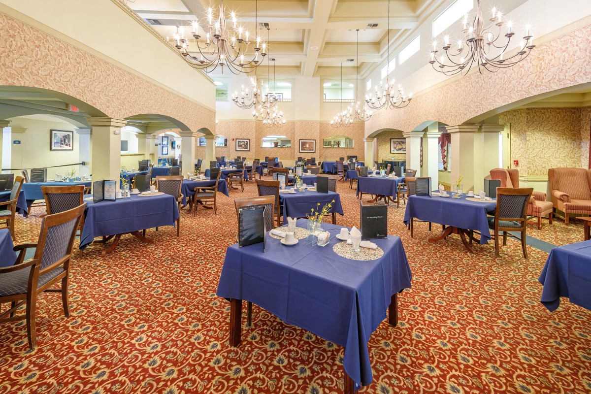 An elegantly designed banquet hall with blue tablecloths and chandeliers.