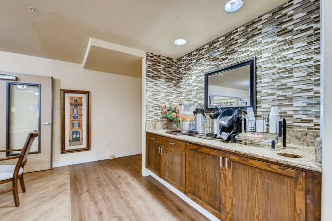 A modern kitchenette featuring a coffee station with wooden cabinets and stylish decor.