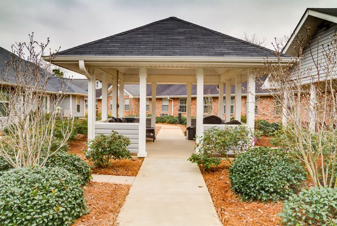 A landscaped pathway leads to a gazebo surrounded by greenery.
