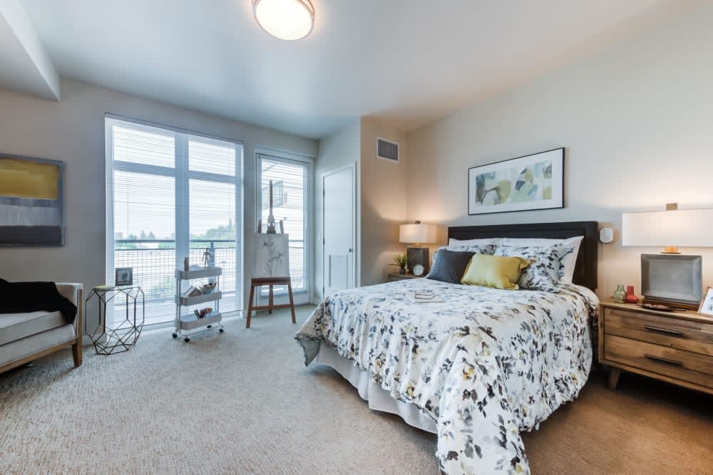 A modern and cozy bedroom with a large window allowing natural light, featuring stylish decor and comfortable bedding.