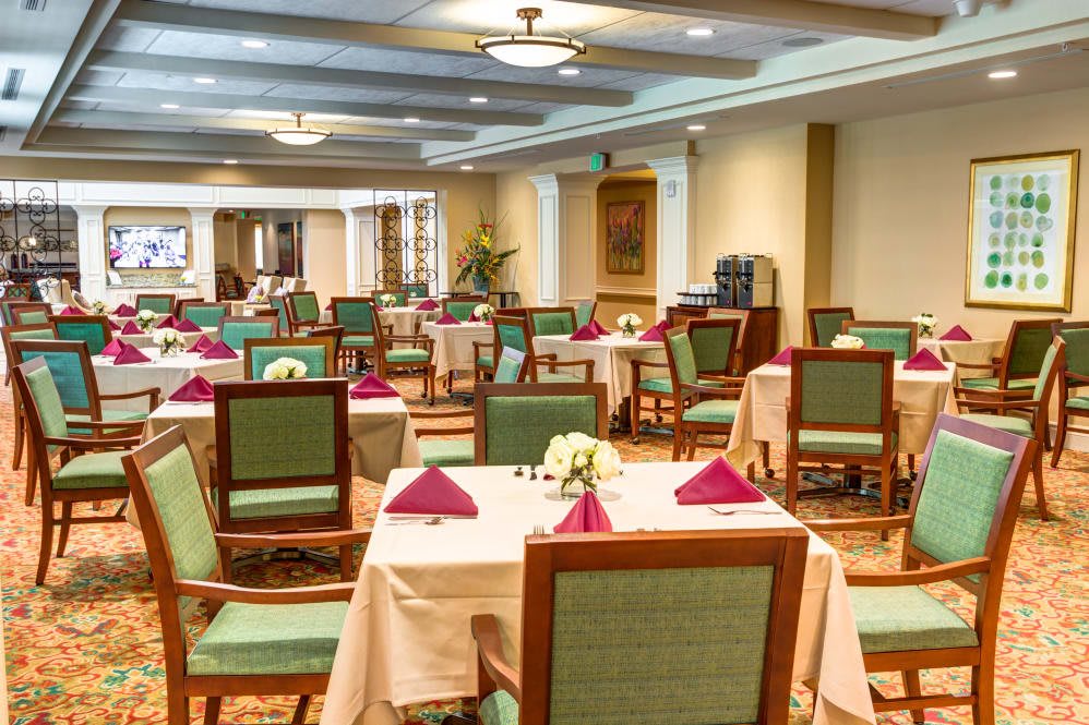 An elegant dining hall with neatly arranged tables and chairs, adorned with decorative napkins and flowers.
