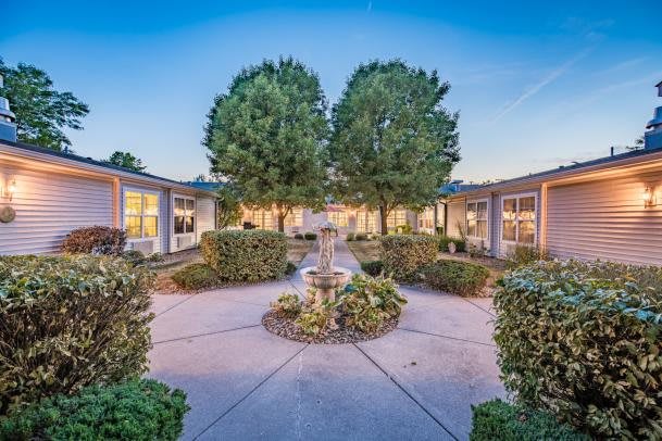 A serene courtyard with a central fountain, surrounded by lush greenery and buildings.