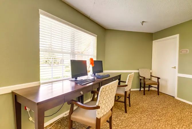 A quiet office space with computers and chairs next to a large window.