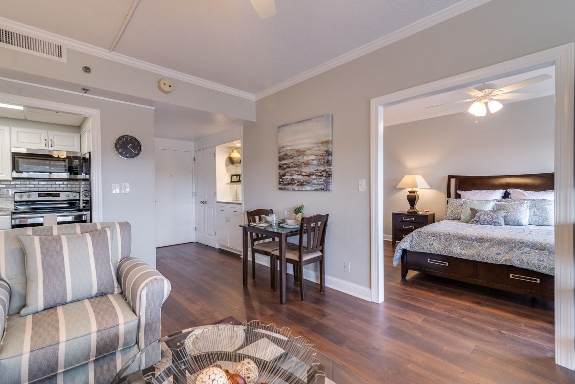 A cozy living space with a small dining area and an adjoining bedroom, featuring modern decor and hardwood flooring.