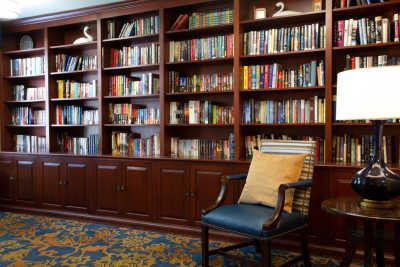 A cozy library corner featuring a well-stocked bookshelf and a comfortable chair.