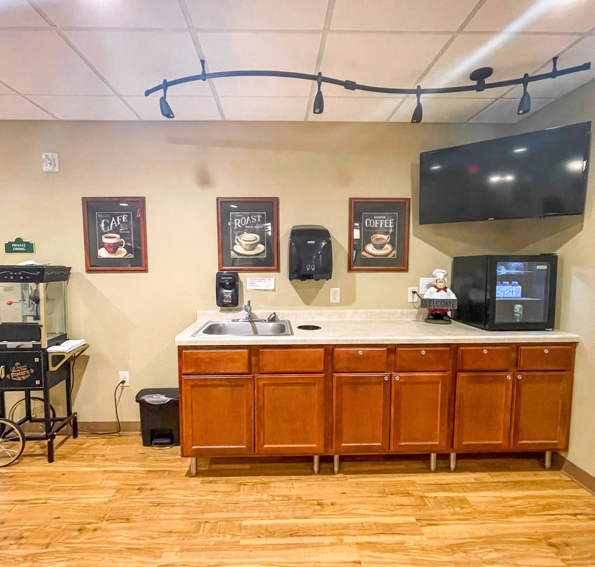 A cozy coffee station with wooden cabinets and a coffee machine in an office setting.