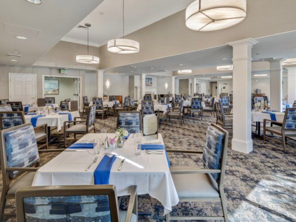 A spacious dining room with elegant decor, set with tables and chairs under modern lighting fixtures.