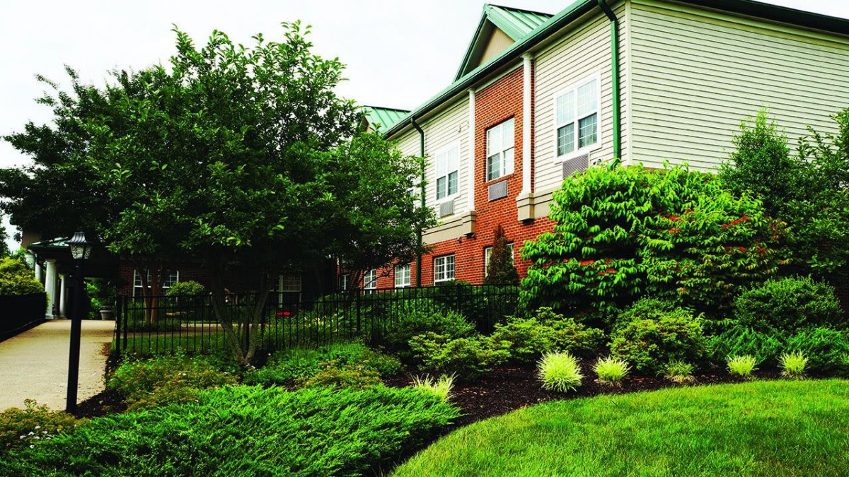 A well-landscaped residential building with a brick facade and lush greenery.