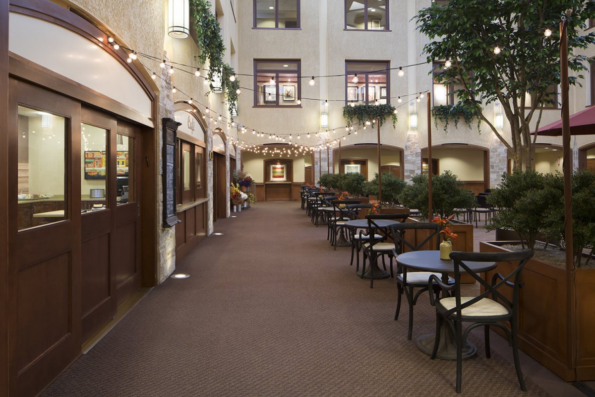 A cozy indoor courtyard with restaurant seating and string lights.