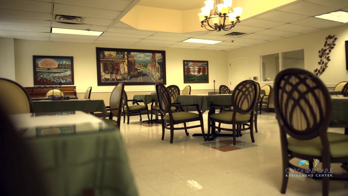 An empty dining area with chairs and tables under a chandelier.