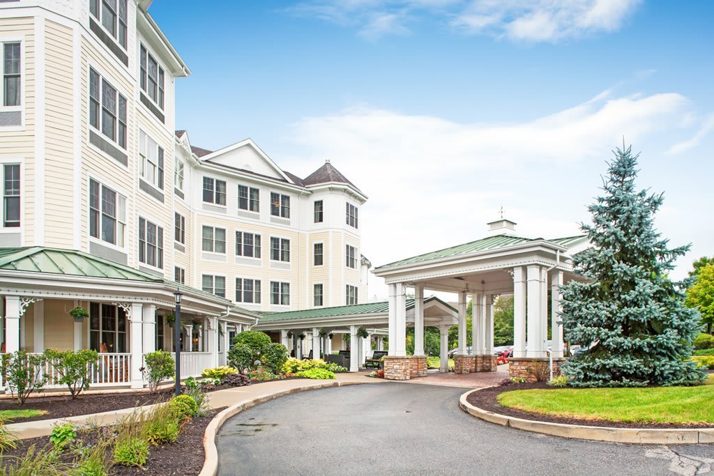 A large residential building with a covered entrance and landscaped driveway.