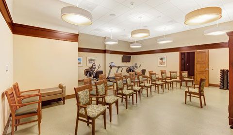 A well-lit room with rows of chairs and exercise equipment, including treadmills.