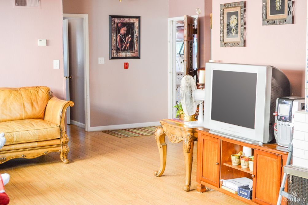 A cozy living room with a television, decorated with artwork and comfortable furniture.