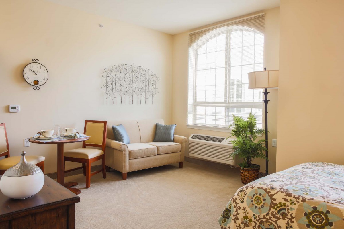 A cozy living room with a sofa, table, and a large window allowing natural light.