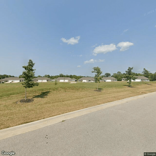 A suburban landscape with a road, trees, and a clear sky.