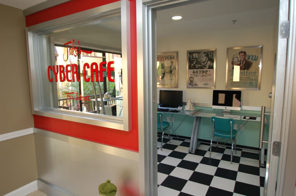 A retro-style cyber cafe with computers, checkered flooring, and bright decor.