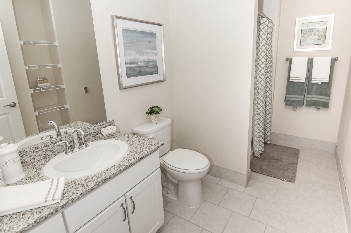 A modern bathroom featuring a sink, toilet, and shower with a patterned curtain.
