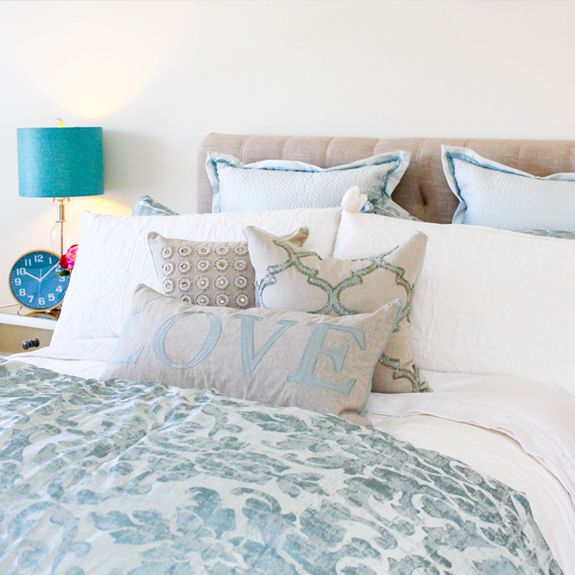 A cozy and stylish bedroom with elegant bedding and decorative pillows.