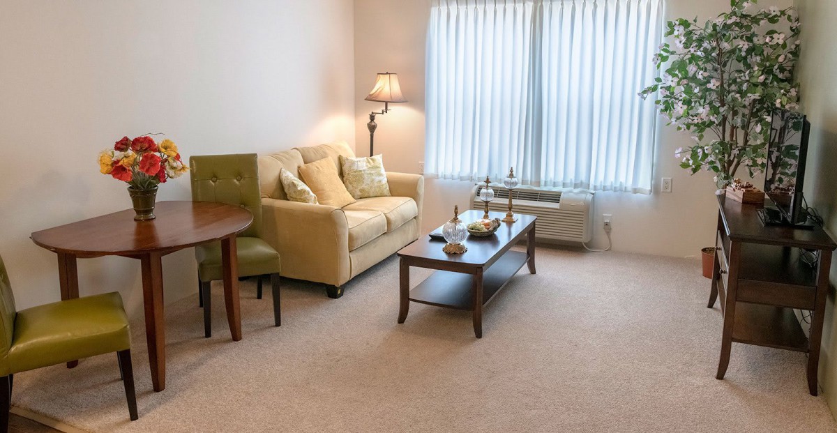 A cozy living room with a sofa and coffee table, softly lit by a floor lamp.