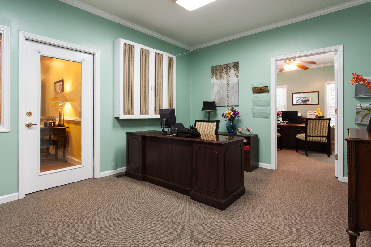 A well-organized office space with a wooden desk, computer, and comfortable seating.