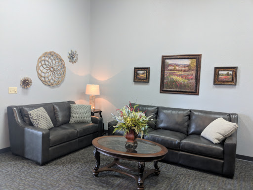 A cozy living room setup featuring comfortable sofas, a coffee table with floral arrangement, and decorative wall art.