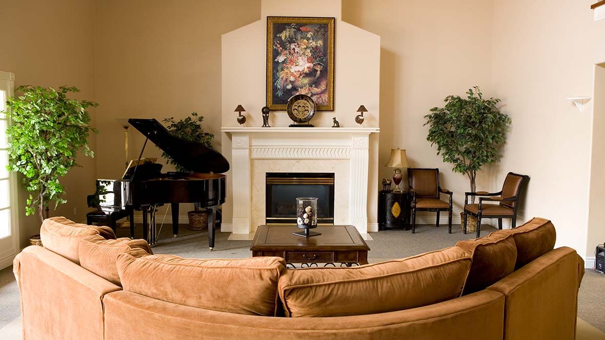 A cozy living room with a fireplace, grand piano, and stylish decor.