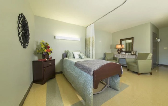 A well-appointed hospital room with a bed and comfortable furnishings.