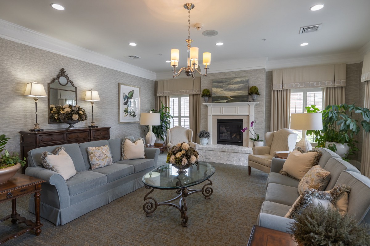 A cozy and elegantly designed living room featuring a chandelier, fireplace, and comfortable seating.